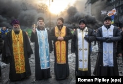 Priests stand in front of a burning barricade on January 23.