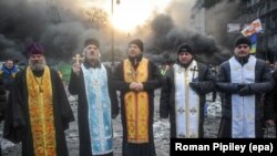 Svećenici stoje ispred zapaljenih barikada 23. januara.
