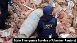 Спасатели убирают неразорванную российскую бомбу с места падения, очищая территорию в Чернигове. Украина, 21 апреля 2022 года
