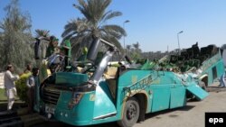 Pakistani security officials inspect the wreckage of a passenger bus at the scene of an accident in Khairpur district of Sindh province on November 11, 2014.