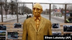 مجسمه پوتین در مقابل عکس‌هایی از قربانیان جنگ در اوکراین و سوریه