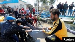 Iraqi rescue workers remove a body from the water where an overloaded ferry sank in the Tigris River.