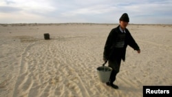 A Kazakh villager carries a bucket of water from a well in a desert that once formed the bed of the Aral Sea. (file photo)