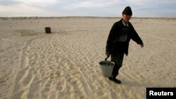 Местный житель несет ведро с водой из колодца посреди пустыни на месте Аральского моря в Казахстане.