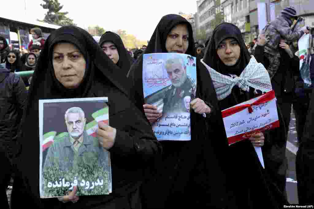 Mourners holding posters of Iranian General Qasem Soleimani.