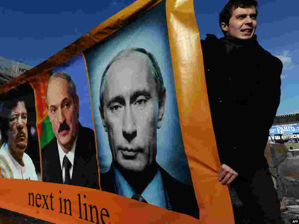 Opposition activists hold a banner with portraits of Libyan leader Muammar Qaddafi, Belarusian President Alyaksandr Lukashenka, and Russian Prime Minister Vladimir Putin titiled "Next in line" during their authorized rally at Pushkin Square in Moscow on March 13. Photo by Andrei Smirnov for AFP