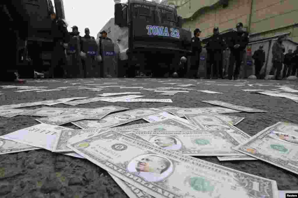 Turkish riot police secure an area as fake U.S.dollar notes with the image of Prime Minister Recep Tayyip Erdogan are seen spread across a road leading to a building belonging to the ruling AK Party during a protest against Erdogan and his government in Ankara. (Reuters/Umit Bektas)