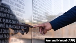A Kosovar Albanian man points at a memorial wall as he views the names of "martyrs" in the village of Marina. (file photo)
