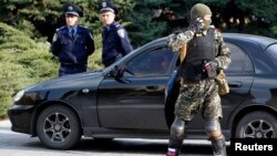 Мужчина в военной форме и в бронежилете стоит рядом со зданием Донецкой областной администрации. 22 апреля 2014 года.