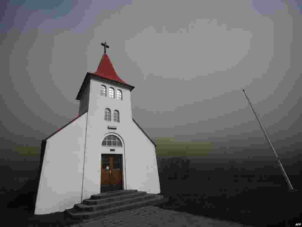 Smoke and ash from the Eyjafjallajokull volcano block daylight around a church near Asolfssakali. Photo by Emmanuel Dunand for AFP.