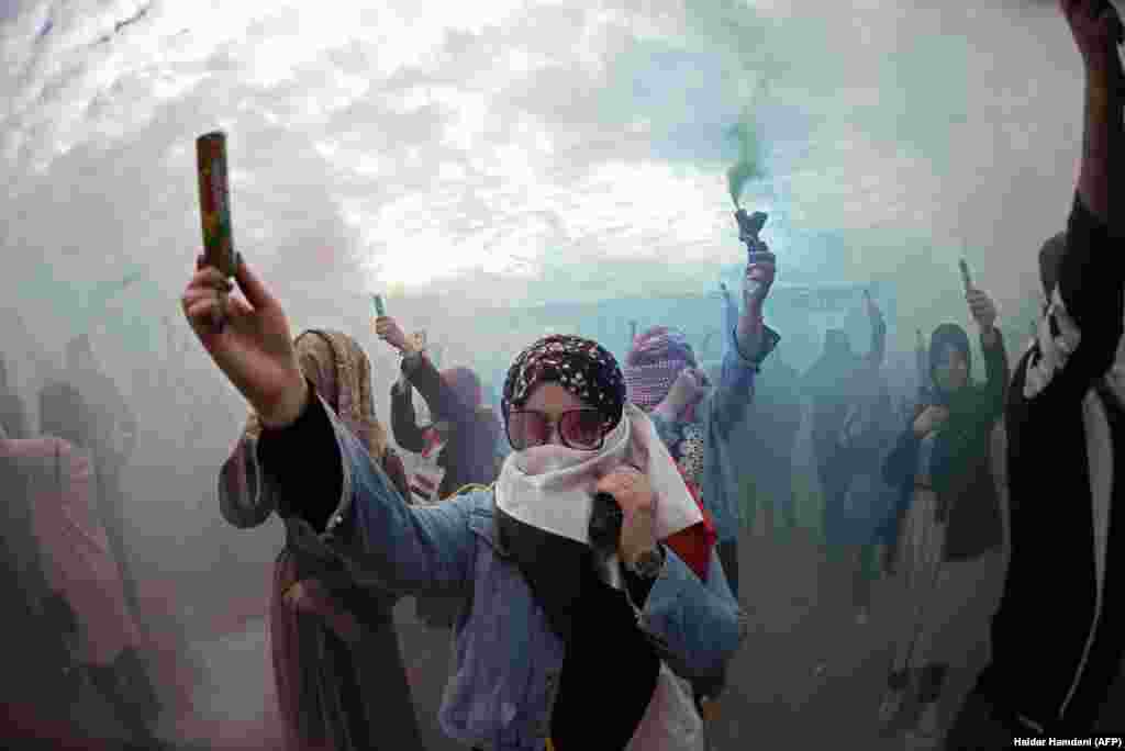Iraqi demonstrators carry cartridges, which release colored smoke, at a festival outside the Kufa University in the holy shrine city of Najaf, Iraq. (AFP/Haidar Hamdani) 