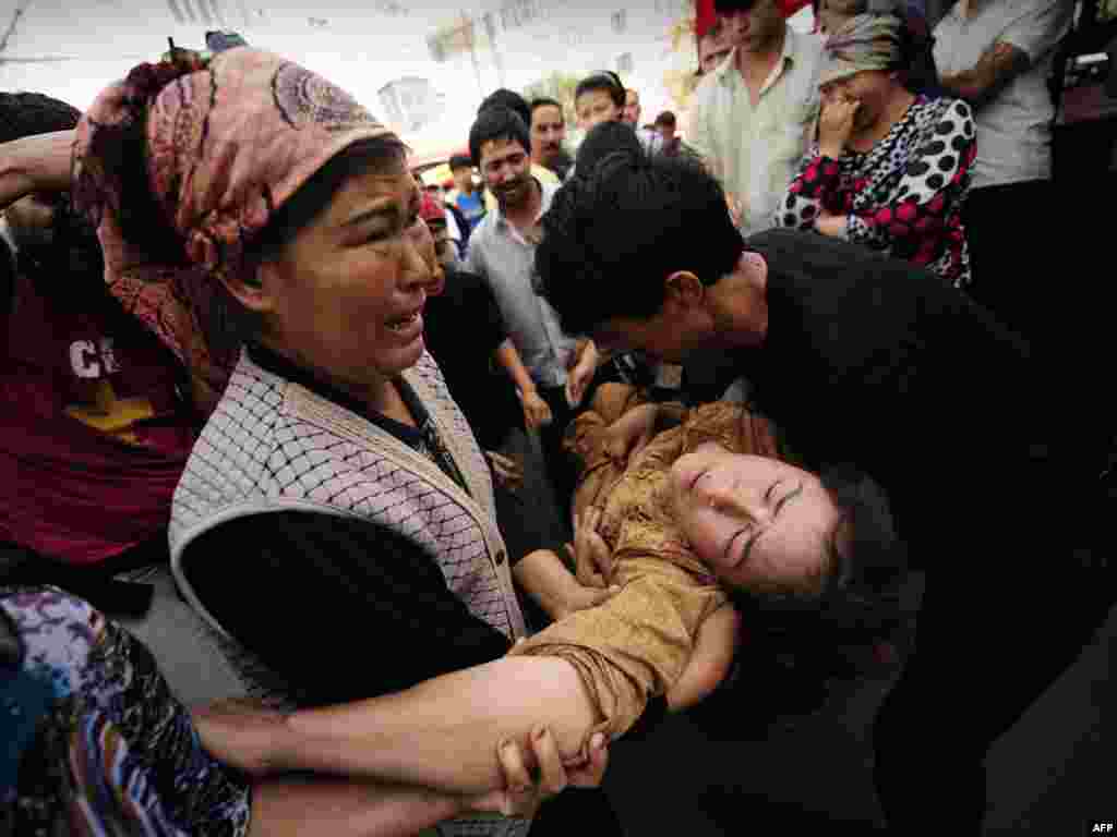 Ethnic Uyghurs carry a woman who fainted during clashes between members of the Uyghur minority and Han Chinese in Urumqi in China's far west Xinjiang Province on July 7.