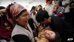 شماری از اقلیت مسلمان ایغور یک خانم را که در جریان اعتراضات در ایالت شین جین ضعف کرده به شفاخانه انتقال می‌دهند. 07 جولای 2009