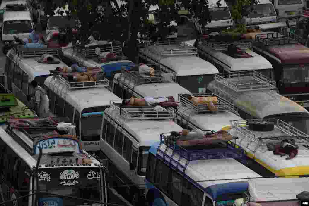 Pakistanly tämizlik işgärleri we awtobus sürijileri ir säher maşynlaryň üstünde uklap ýatyrlar. Lahor. &nbsp;(AFP/Arif Ali)