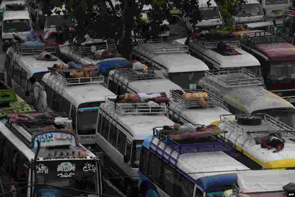 Pastrues pakistanez dhe shoferët e autobusëve duke fjetur mbi automjete, herët në mëngjes në Lahore.&nbsp;