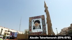 ماکتی از موشک شهاب-۳ ایران در کنار تصویری از رهبر جمهوری اسلامی در میدان بهارستان تهران؛ گفته می‌شود این موشک تا دو هزار کلیومتر برد دارد.