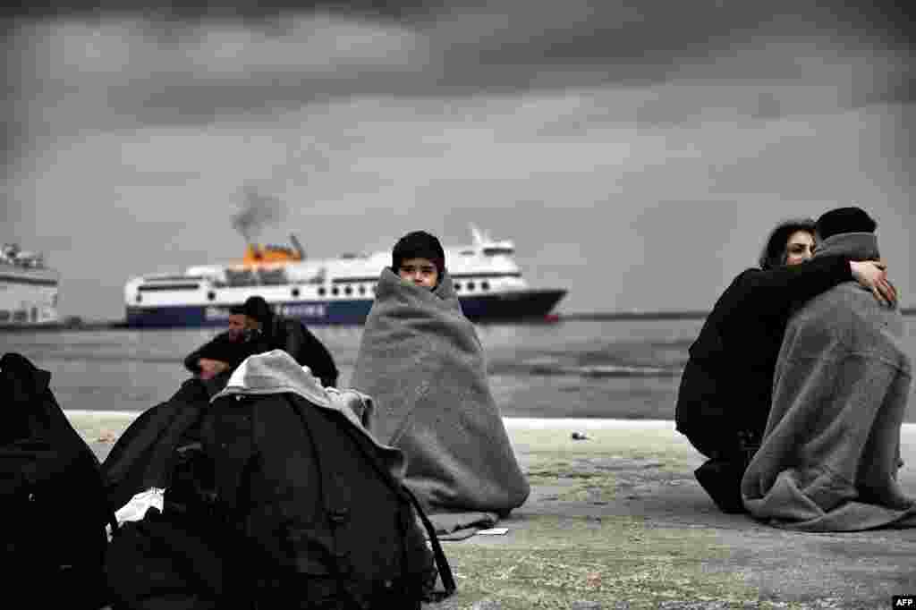 Children wrap up against the cold in a harbor as migrants and refugees arrive on the Greek island of Lesbos after crossing the Aegean Sea from Turkey. (AFP/Aris Messinis)