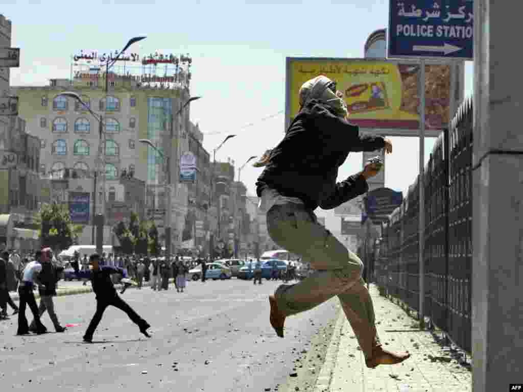 A Yemeni antigovernment protester jumps to throw stones toward a police station during clashes with regime loyalists in central Sanaa on February 17. At least 12 people were injured and police fired warning shots during the fierce clashes.Photo by Ahmad Gharabli for AFP