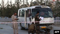 AFGHANISTAN -- Afghan security personnel investigate a damage bus carrying employees of Khurshid TV, at the site of a sticky bomb blast in Kabul, August 4, 2019