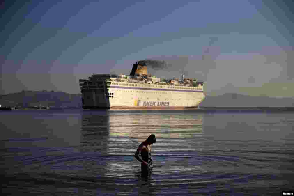 A migrant bathes as the passenger ship Eleftherios Venizelos leaves port on the Greek island of Kos. The ship -- carrying Syrian refugees -- was headed for the mainland as authorities struggle to cope with a wave of arrivals. The ship had acted as a floating accommodation and registration center and was heading for the northern port of Thessaloniki. (Reuters/Alkis Konstantinidis)