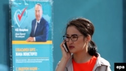 Девушка рядом с объявлением о дате проведения в Казахстане внеочередных выборов. Астана. 24 апреля 2015 года.