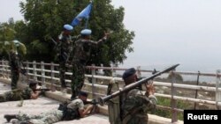 Lebanese soldiers take up positions as UN peacekeepers gesture toward Israeli soldiers at the Lebanese-Israeli border in the Lebanese village of Adaisseh on August 3.