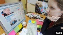 A woman looks at a computer monitor displaying the main page of Prime Minister Vladimir Putin's election campaign website.