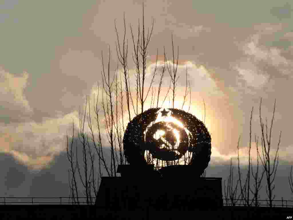 A sculpture depicting the symbol of the former U.S.S.R. is set against the setting sun in the abandoned city of Pripyat close to Chornobyl on March 31. The project to build a new sarcophagus over the damaged Chornobyl nuclear reactor lacks some 600 million euros ($850 million) of the 1.5 billion needed, a Ukrainian official said. Photo by Sergei Supinsk for AFP
