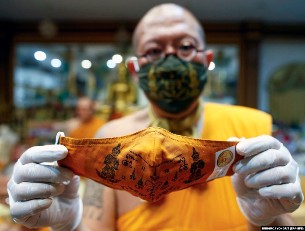 Thai Buddhist abbot monk Phra Kru Palad Sitthiwat holds a face mask he inscribed with spiritual incantations in Thailand's Nakhon Pathom Province on March 29.