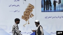 Pedestrians walk past a bank advertisement board offering loans in Kabul in 2011.