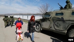 Женщины проходят мимо военной машины. Село Перевальное близ Симферополя. 14 марта 2014 года.