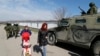 Women walk past a Russian GAZ Tiger infantry vehicle near a Ukrainian military unit in the village of Perevalnoye, outside Simferopol, Ukraine, on March 14.