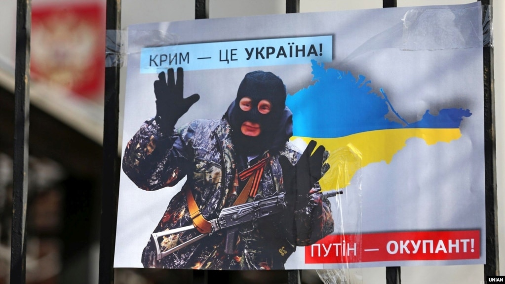 Плакат із зображенням президента Росії Володимира Путіна у вигляді «зеленого чоловічка» під час акції «Крим – це Україна» біля тодішнього російського посольства в Києві, 16 березня 2020 року
