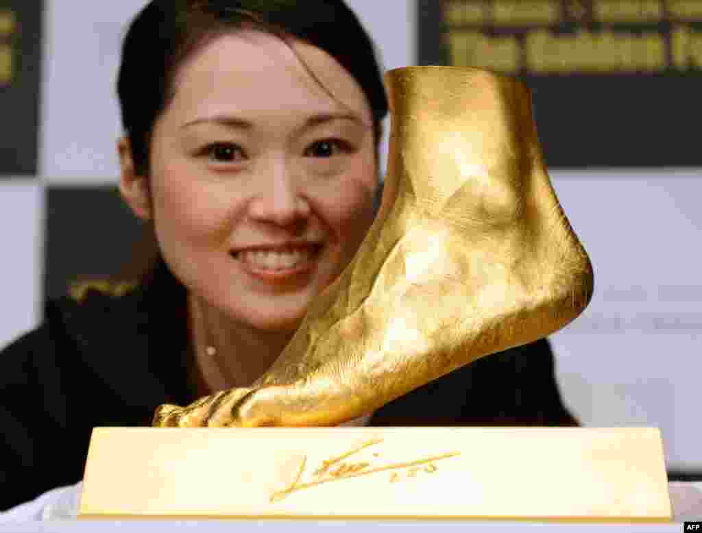 An employee of Ginza Tanaka poses beside the golden replica of the left foot of football star Lionel Messi of Argentina. Priced at about $5.25 million, the 25-kilogram golden foot was created by the Tokyo-based jewelry retailer to commemorate Messi's record-breaking Ballon d'Or for four consecutive years and the world-record 91 goals he scored in a calendar year. (AFP/Toshifumi Kitamura)