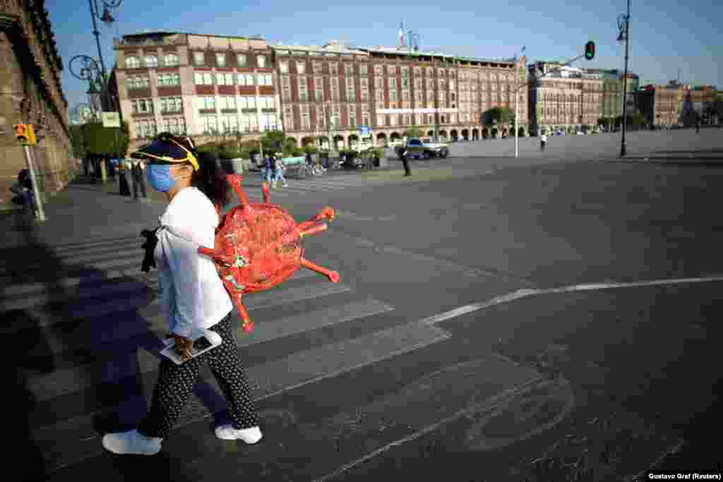 Pinata de pandemie. O demonstrantă poartă o pinata în formă de coronavirus la un protest din Mexico City, pe 31 martie. Populară la petrecerile de naștere ale copiilor din America Latină, pinatele sunt făcute din hârtie creponată, umplute cu bomboane și agățate pentru a fi rupte cu bastoane de către o persoană legată la ochi.