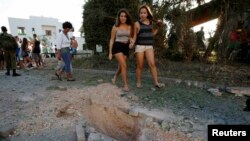 Onlookers walk past damage caused by a rocket fired from Lebanon into Israel near the northern city of Nahariya on August 22.