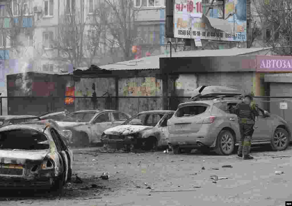 An Ukrainian serviceman inspects a damaged car.