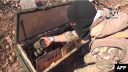 A video grab purportedly shows an IS militant displaying the contents of a crate of grenades reportedly intended for Kurdish militias but which fell into the hands of Islamic State militants near the town of Kobani.