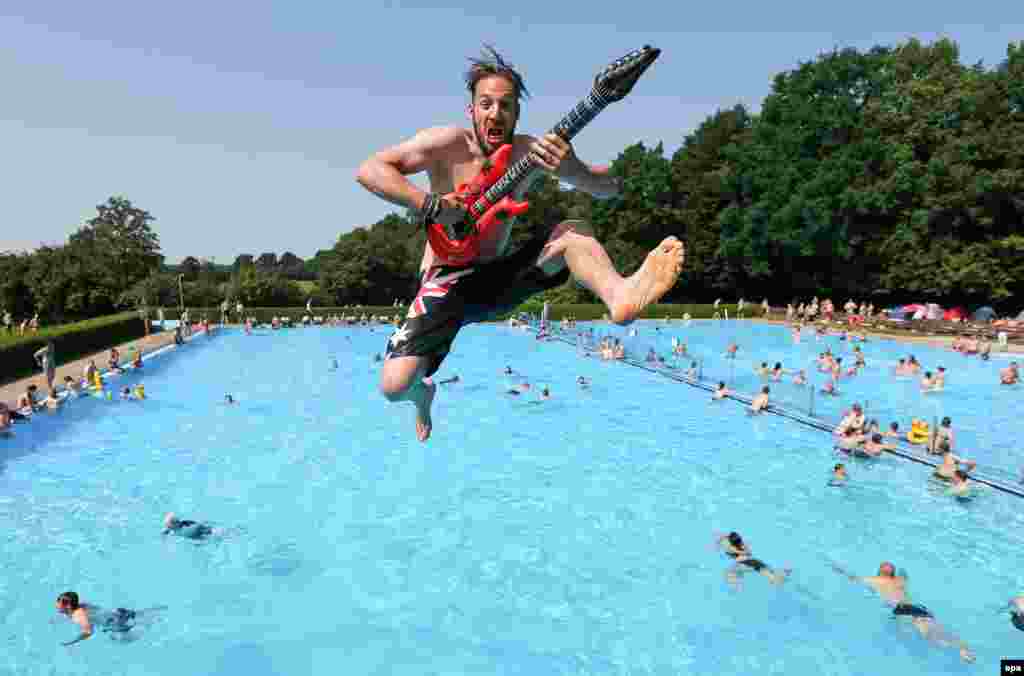 Ahead of a major heavy metal festval, Benni from Dortmund jumps from a three-meter tower into swimming pool with an inflatable guitar in Wacken on August 1. (epa/Axel Heimken)