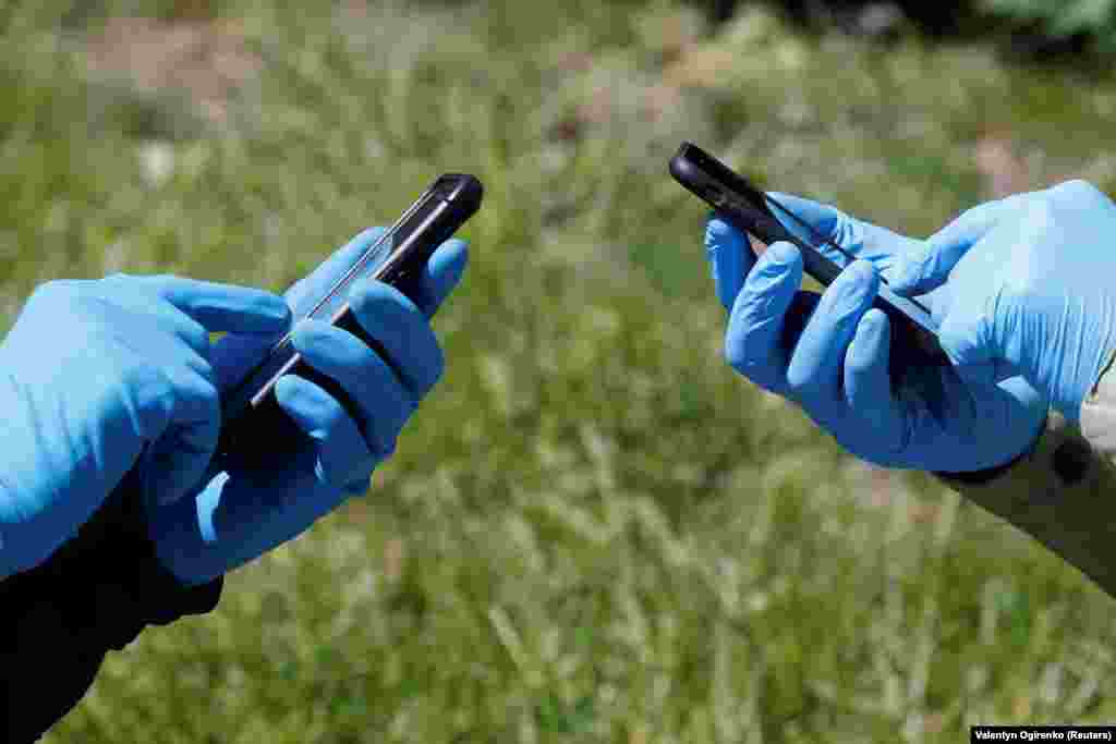 Луѓе кои носат заштитни ракавици ги користат своите паметни телефони во Киев, Украина на 13.05.2002 година.