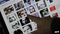 A man points to pictures of people allegedly killed during the 1982 Hama massacre on a Facebook page titled "Hama."