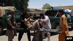 Afghan men carry a victim of a powerful car bomb in Lashkar Gah on June 22.