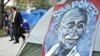 U.S. - Businessmen pass by a sign featuring Mahatma Ghandi in the Occupy DC camp early in McPherson Square in Washington, DC, 18Oct2011