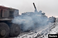 A Ukrainian military truck tows a tank damaged during fighting with pro-Russian separatist forces outside Debaltseve on February 10.