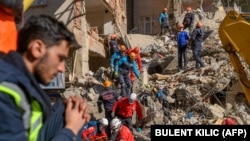 Rescue workers work on January 25 amid the rubble of a building after an earthquake in Elazig, Turkey.