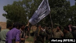 The Afghan forces hold a Taliban flag after overrunning an insurgent hideout in Marjah on July 22. 