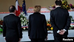 French President Francois Hollande (left), German Chancellor Angela Merkel (center), and Spain's Prime Minister Mariano Rajoy pay their respects on March 25 at a makeshift morgue prepared for the 150 victims who died in the crash.