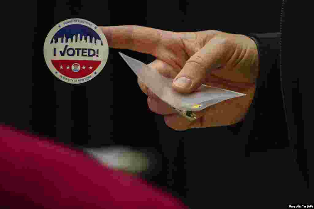 Választási matricát adott át egy dolgozó egy szavazónak a választás első órájában New Yorkban.