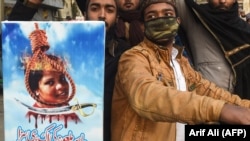 FILE: Pakistani Islamists hold a poster displaying the portrait of Asia Bibi, a Christian Pakistani woman accused of blasphemy, during a protest against the Supreme Court decision on Bibi's case in Lahore in February.