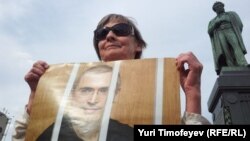 A woman in Moscow holds a portrait of Mikhail Khodorkovsky to mark his continued imprisonment on his birthday in June 2012.